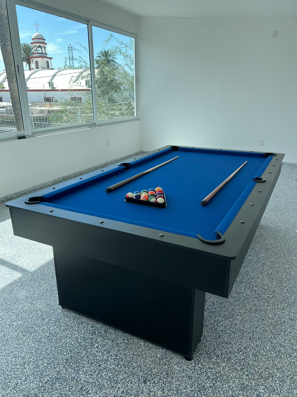 Mesa negra con paño azul junto a ventanal