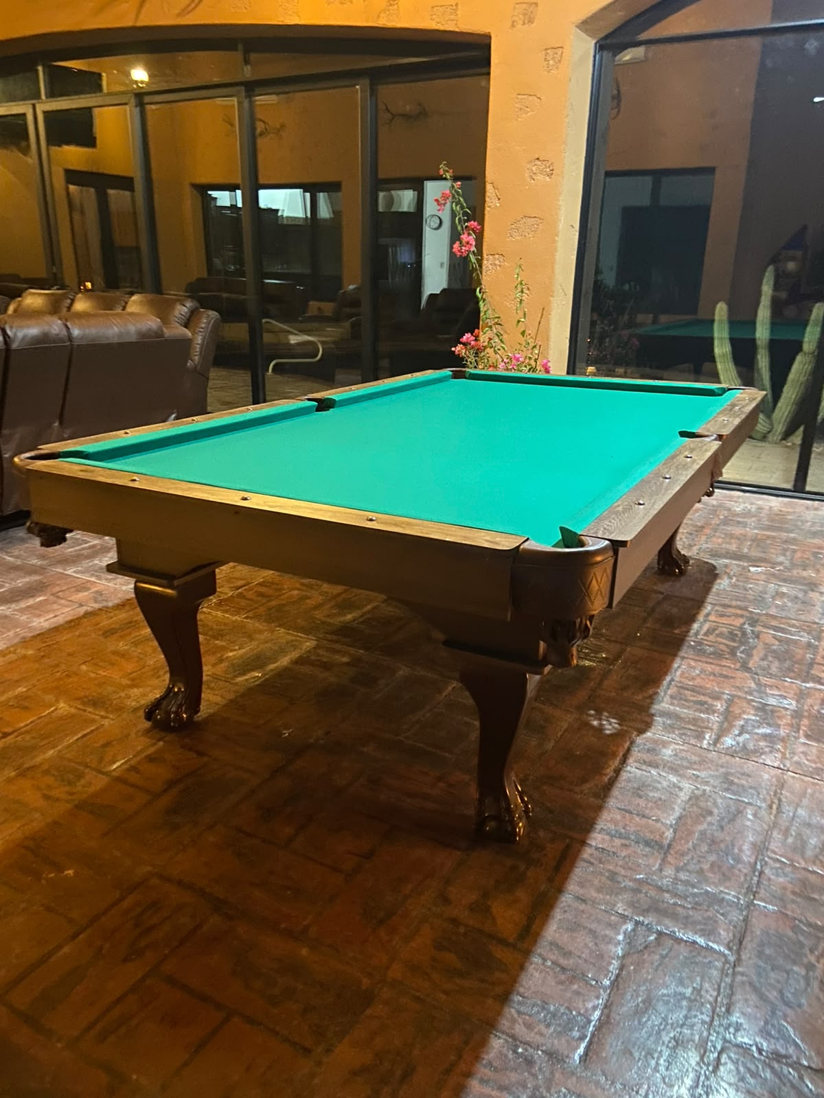 Mesa con paño verde y patas talladas en terraza